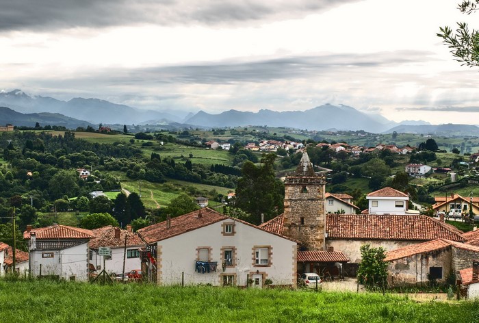 Village with church tower and mountains in Comillas, Spain