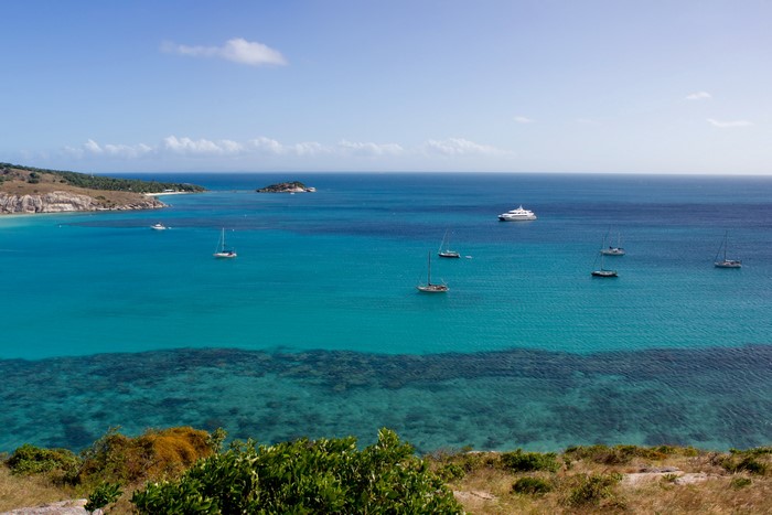 Sailboats and yachts in a turquoise bay near a tropical island