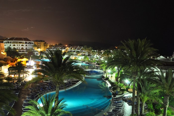 Resort with pools and palm trees at night in Tenerife, Spain