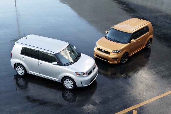 Two Scion xB cars parked on a wet surface