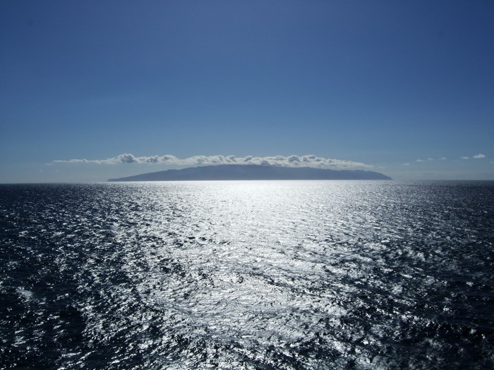 Island on the Horizon with Sunlit Ocean and Clouds