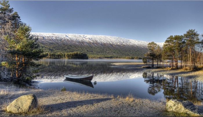 Boat on a lake with snow-capped mountains in Norway