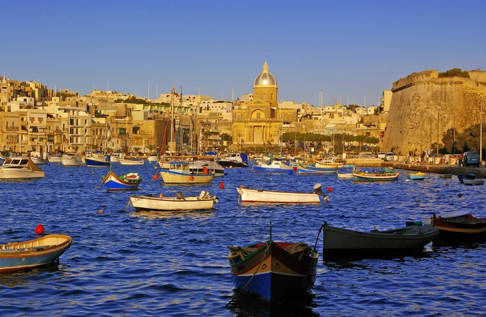 Boats in Kalkara, Malta harbor with buildings and church