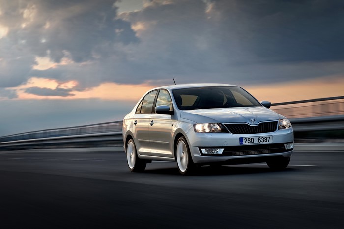 Silver Skoda Rapid driving on a road at sunset