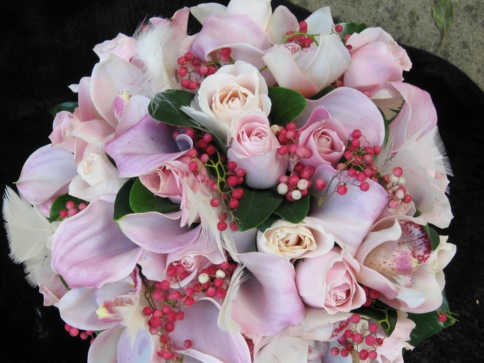 Pink roses and orchids bouquet with berries and feathers