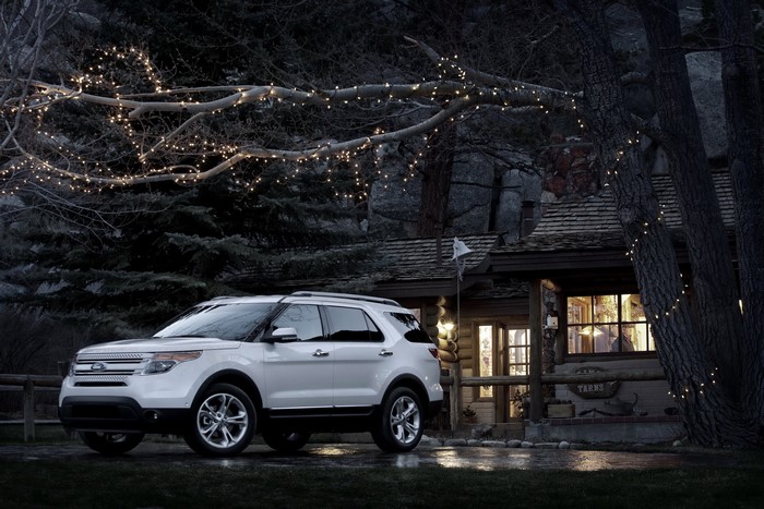 White Ford Explorer parked near a cabin with fairy lights