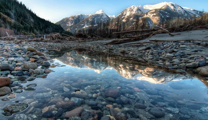 Snow-capped mountains reflected in a shallow stream in Yoho National Park, Canada