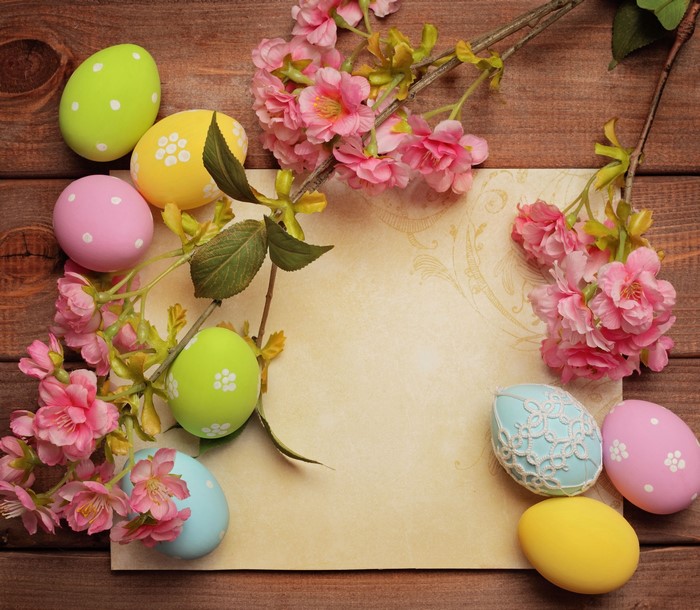 Easter Eggs and Pink Flowers on Wooden Background