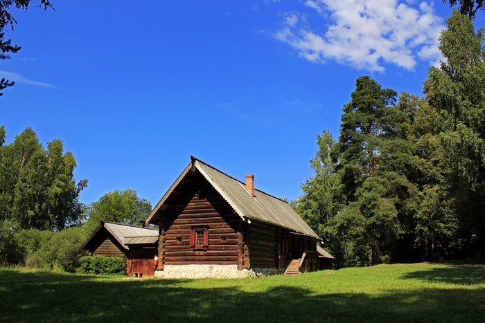 Wooden houses in a grassy field under a blue sky