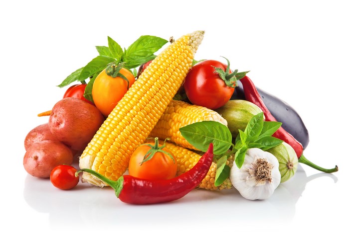 Assortment of fresh vegetables including corn, tomatoes, potatoes, garlic, and peppers