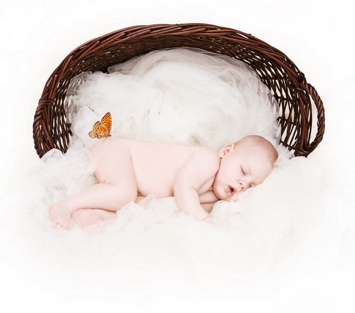 Newborn baby sleeping in a wicker basket with a butterfly