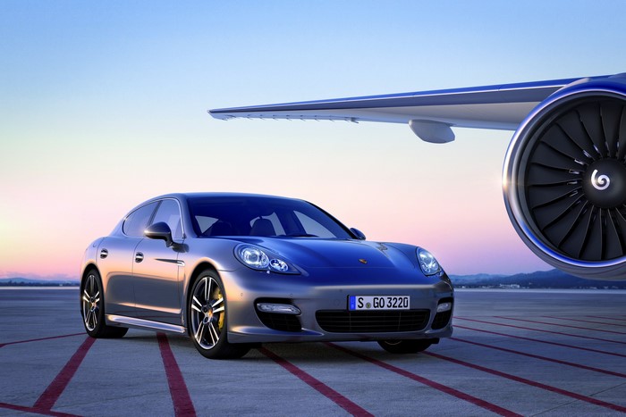 Porsche Panamera Turbo S parked next to airplane engine