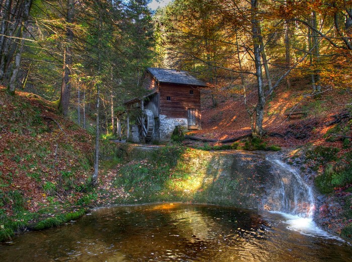 Old watermill in an autumn forest with a waterfall