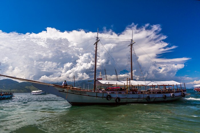 Sailboat with people on the water under clouds