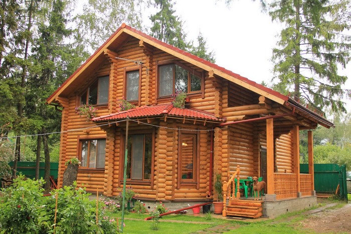 Log cabin house with red roof and porch