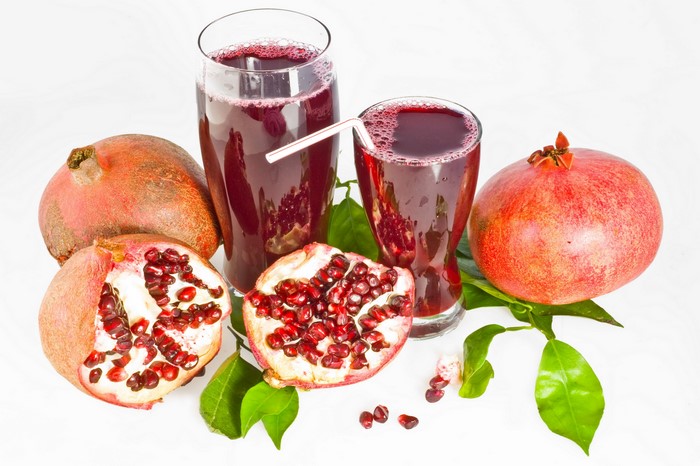 Pomegranate juice in glasses with pomegranates and leaves