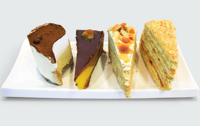 Four slices of cake on a white platter