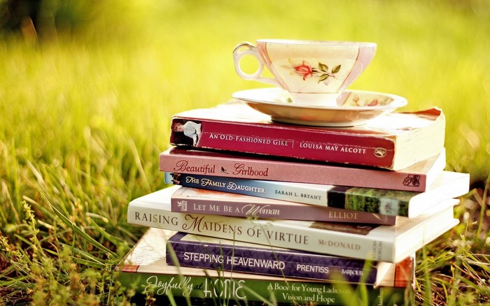 Stack of books with a teacup on top in grass