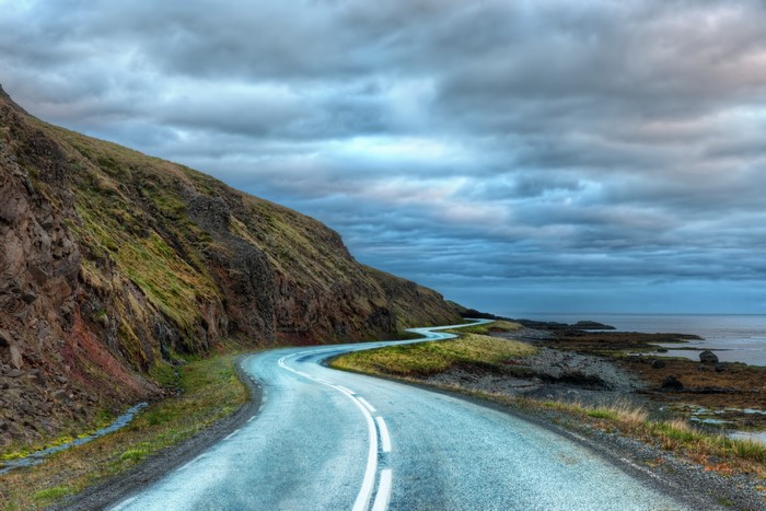 Winding Road by the Sea Under Cloudy Sky