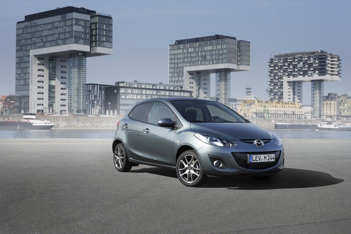 2012 Mazda 2 parked on asphalt with modern buildings in background