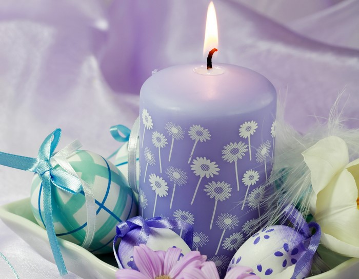 Easter candle with decorated eggs and flowers