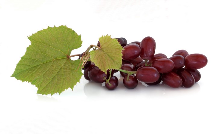 Red grapes with green leaves on a white background