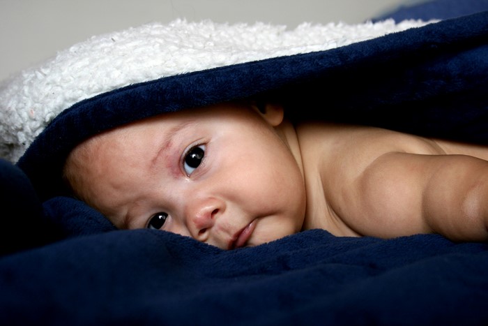 Infant peeking from under a blanket