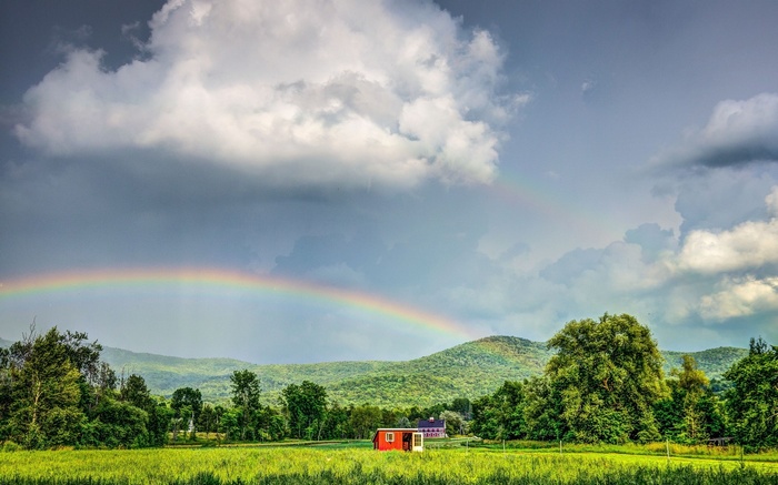 Rainbow over a green landscape with a red building