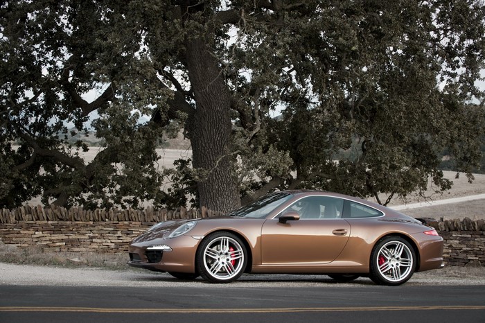 Porsche 991 Carrera S parked by a stone wall
