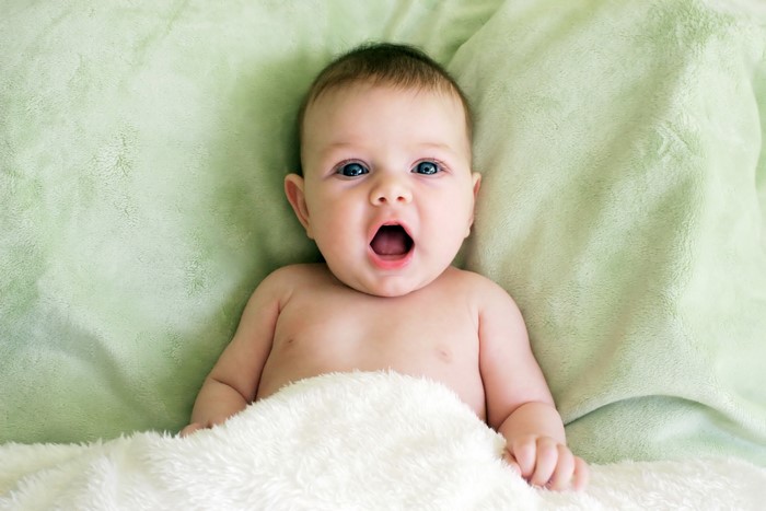Baby yawning on a green blanket
