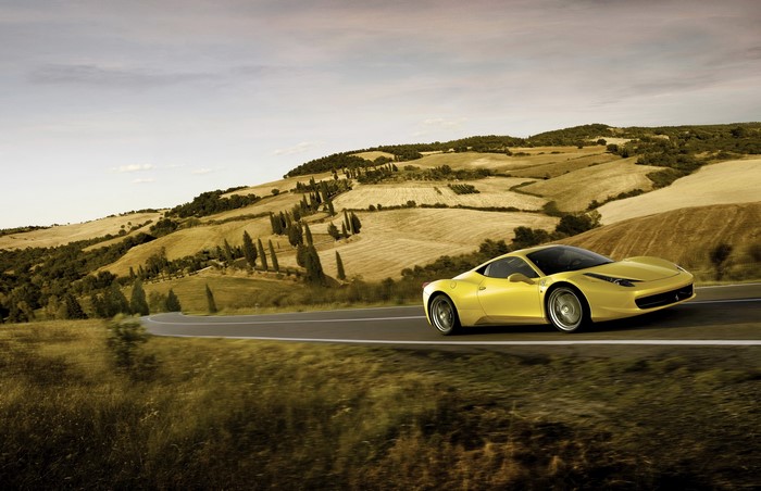 Yellow Ferrari 458 Italia driving on a winding road