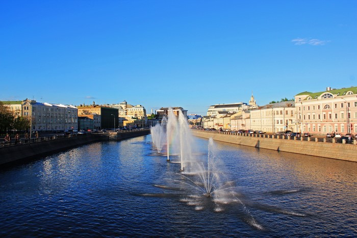 Moscow canal with fountains and buildings under blue sky