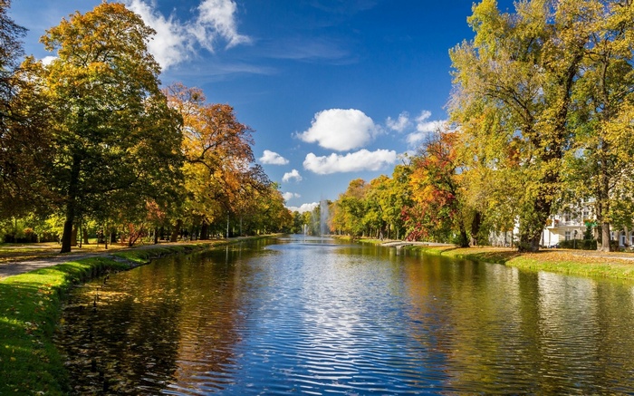 Canal with trees in autumn colors and a fountain