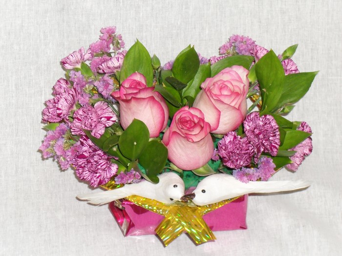 Pink roses and purple flowers in a bouquet with doves