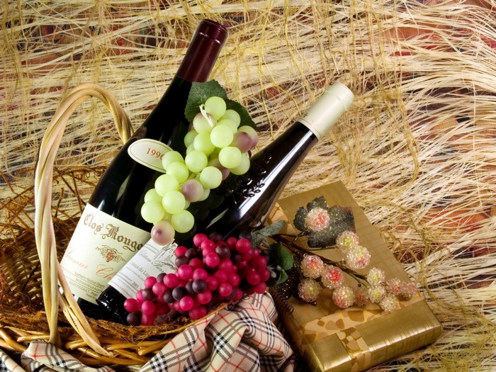 Still-life with wine bottles and grapes in a basket