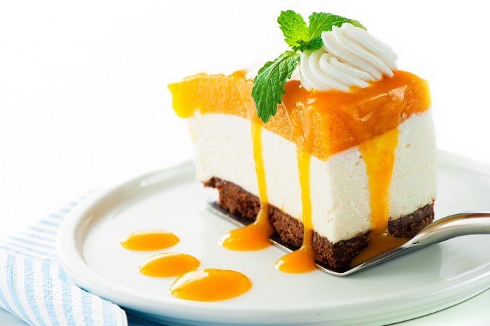 Mango cheesecake slice with whipped cream and mint