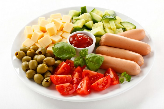 Plate of Vienna sausages, cheese, olives, tomatoes, cucumbers, and ketchup