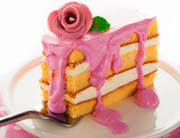 Slice of pink frosted cake with rose decoration