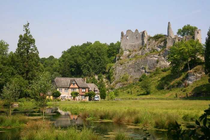 Castle ruins above a house and pond in Belgium