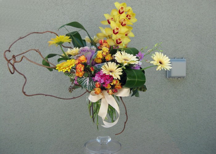 Floral arrangement with yellow orchids and gerbera daisies in a glass vase