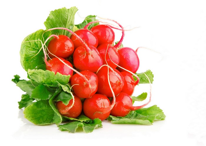 A pile of fresh radishes with green leaves