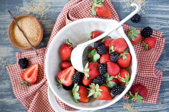 Strawberries and blackberries in a bowl with sugar and vanilla
