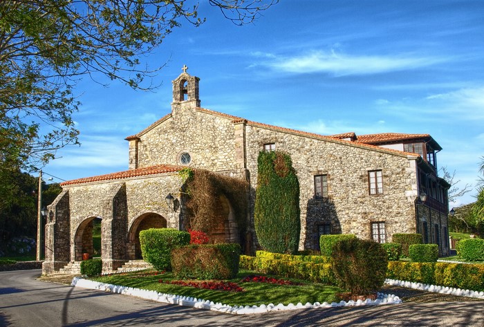 Stone church with arched entrance and gardens in Spain