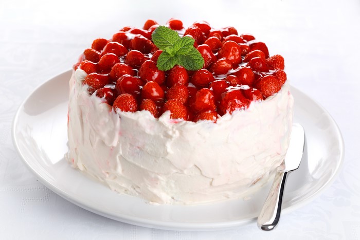 Strawberry cake with whipped cream and mint on a plate