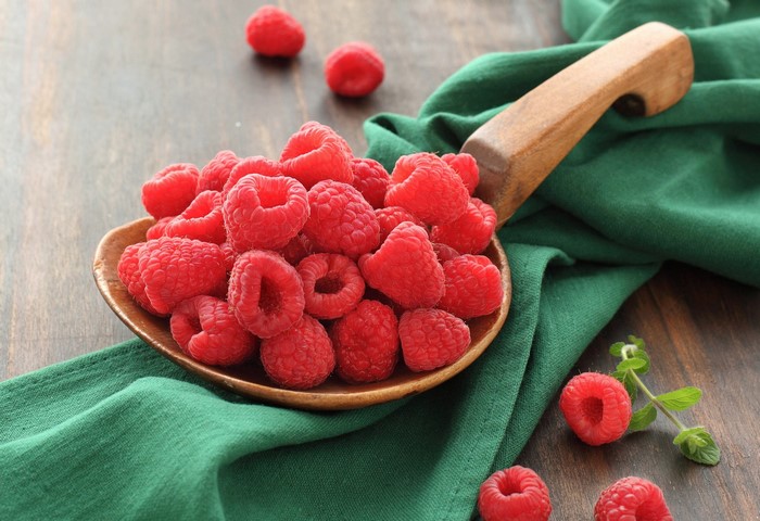 Raspberries in a wooden spoon on a table