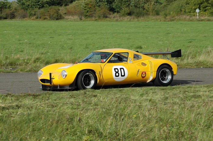 Yellow 1966 Ginetta G12 race car on a track