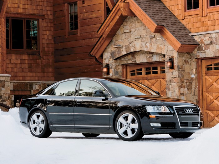 Black Audi A8 parked in front of a wooden house