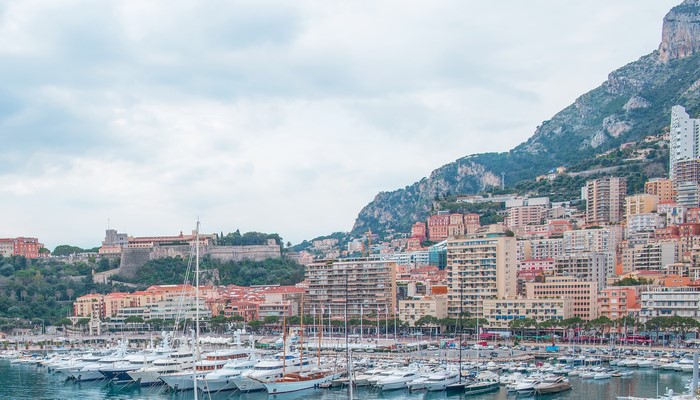 Yachts docked in Monaco harbor with city and mountain backdrop