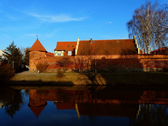 Brick castle tower and wall reflected in water