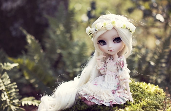 Doll with blonde hair and flower crown sitting on moss